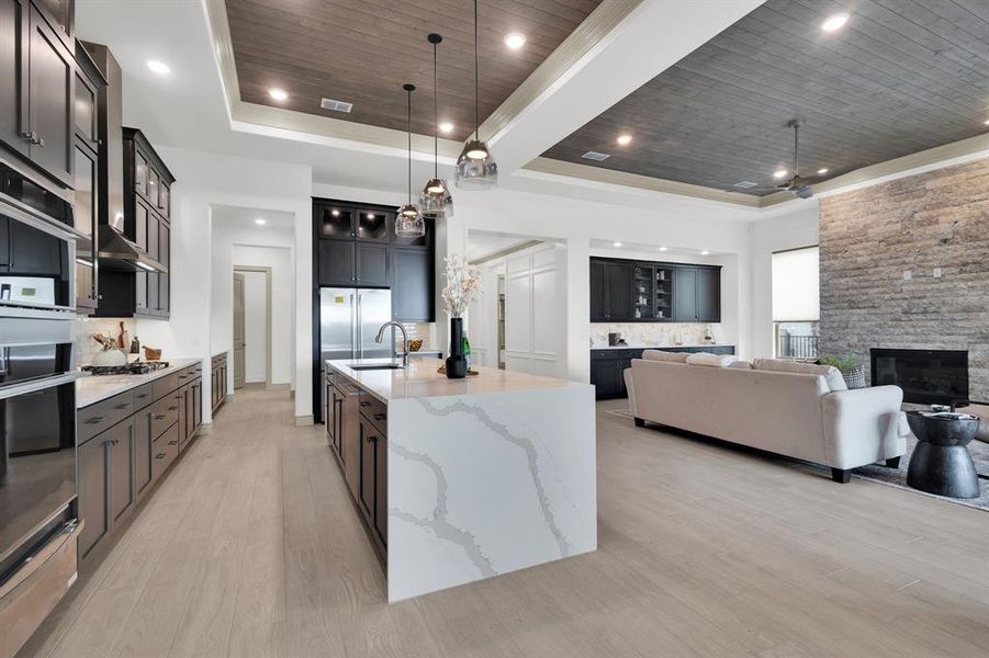 Kitchen featuring wood ceiling, glass insert cabinets, light stone counters, backsplash, and light wood-style flooring