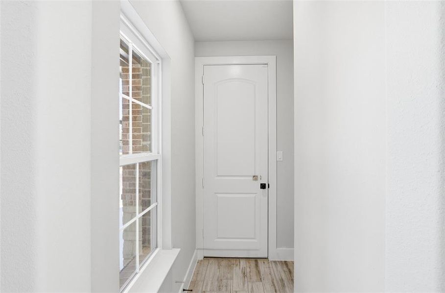 Corridor with light wood-type flooring and baseboards