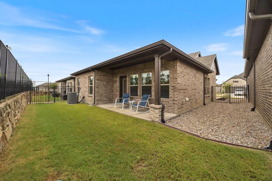 Rear view of house featuring a fenced backyard, brick siding, and a patio area