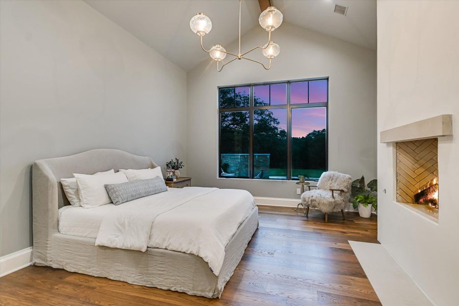 Bedroom featuring wood finished floors, a chandelier, and high vaulted ceiling Bedroom featuring wood finished floors, a chandelier, and high vaulted ceiling