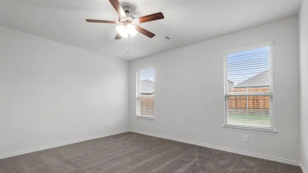 Spare room featuring dark carpet and a ceiling fan Spare room featuring dark carpet and a ceiling fan