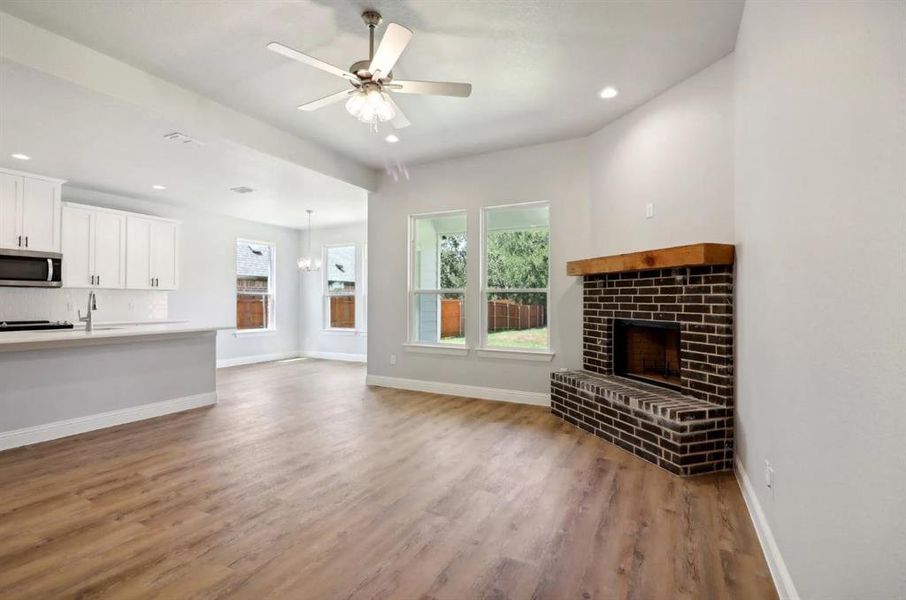 Unfurnished living room with wood-type flooring, ceiling fan, and a fireplace