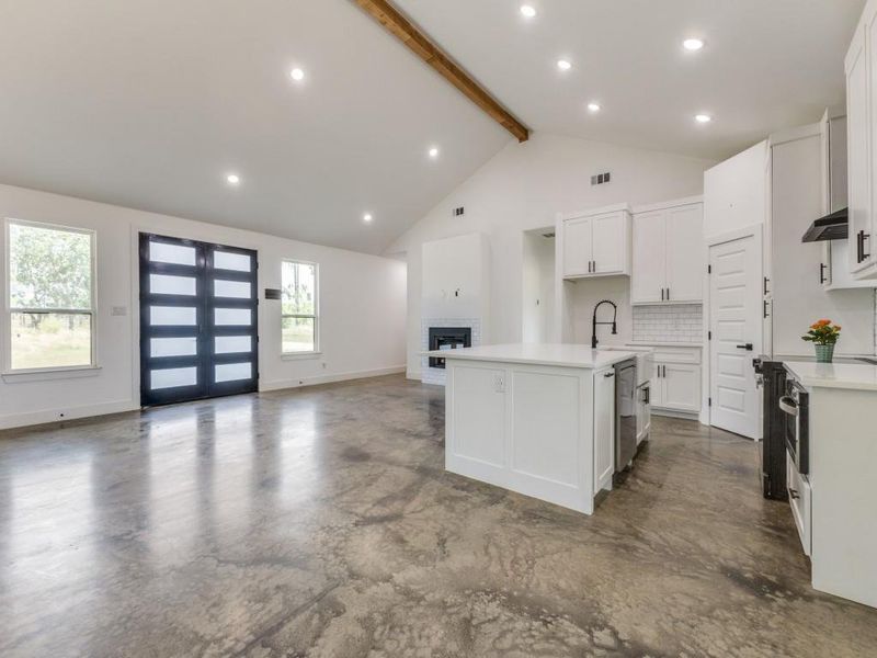 Kitchen with beam ceiling, a center island with sink, open floor plan