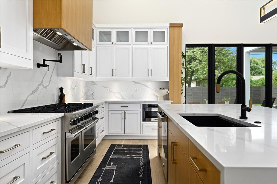 Kitchen featuring light wood-style flooring, white cabinets, double oven range, and a sink