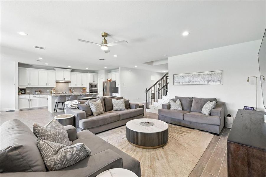 Living area with ceiling fan, recessed lighting, and stairway