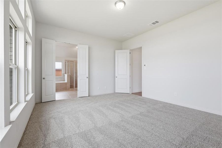 Unfurnished bedroom featuring light carpet and connected bathroom