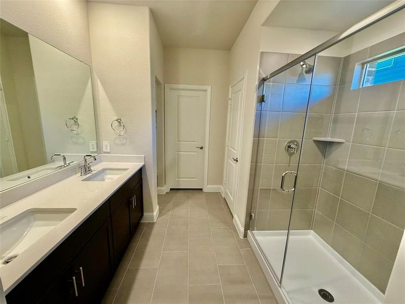 Bathroom featuring a dual-sink vanity with white countertops, dark wood cabinetry, and chrome fixtures Bathroom featuring a dual-sink vanity with white countertops, dark wood cabinetry, and chrome fixtures