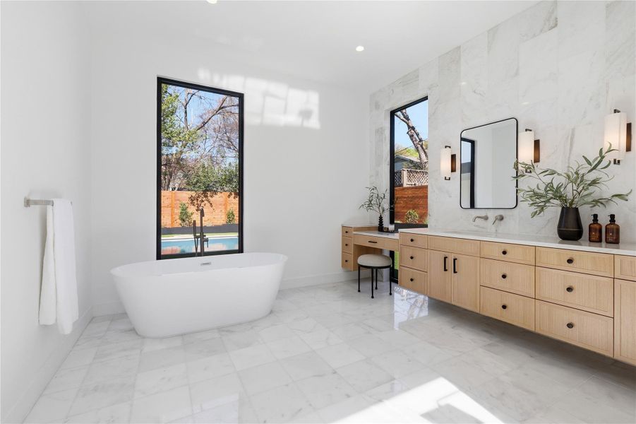 Bathroom featuring vanity, a soaking tub, light marble finish flooring, and recessed lighting