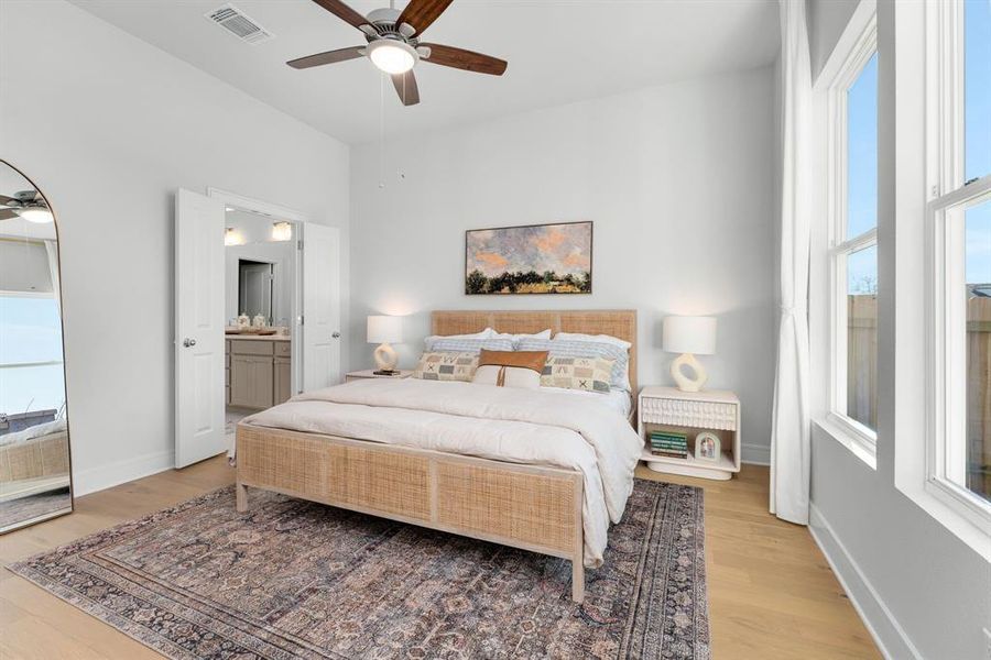 Bedroom with light wood finished floors, a ceiling fan, and ensuite bath