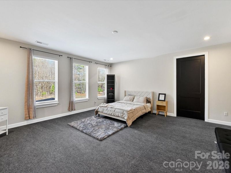 Expansive bedroom featuring plush carpeting, abundant natural light, and ample space for versatile furniture arrangements.