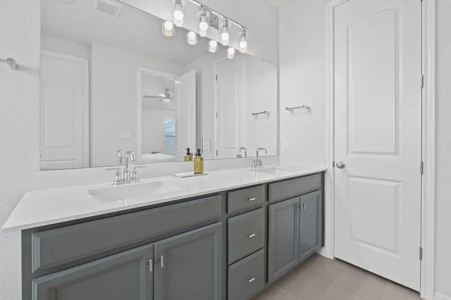 Full bath featuring light tile patterned floors, double vanity, ensuite bathroom, and a ceiling fan Full bath featuring light tile patterned floors, double vanity, ensuite bathroom, and a ceiling fan