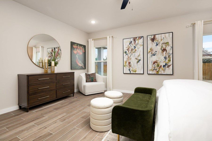 Natural light illuminates this cozy primary bedroom with stylish wood flooring and recessed lighting.