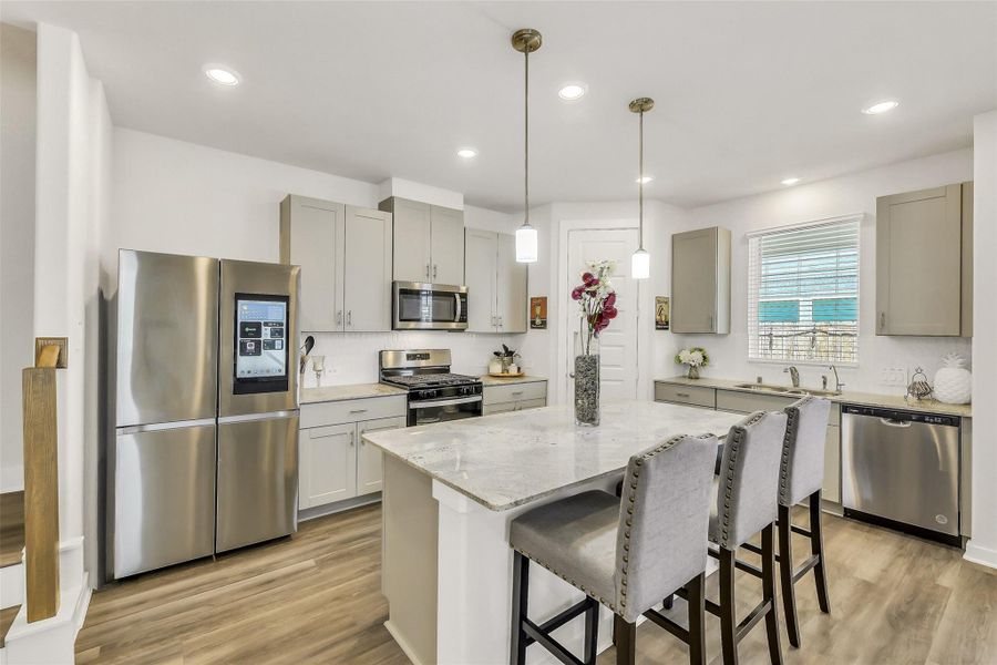 Beautiful chef-inspired kitchen featuring a large center island, sleek countertops, stainless steel appliances, and abundant cabinetry for storage.