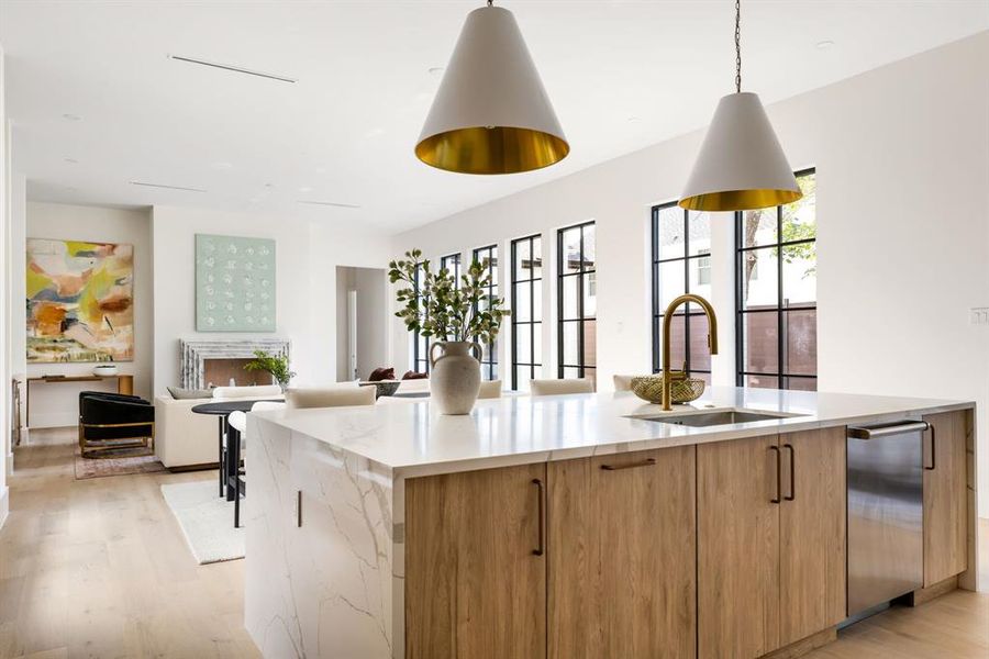 Kitchen featuring modern cabinets, light stone counters, light wood-style floors, brown cabinets, and a large island with sink Kitchen featuring modern cabinets, light stone counters, light wood-style floors, brown cabinets, and a large island with sink