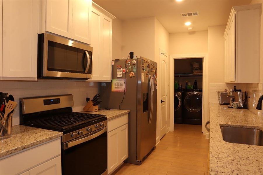 Kitchen featuring appliances with stainless steel finishes, decorative backsplash, white cabinetry, and recessed lighting Kitchen featuring appliances with stainless steel finishes, decorative backsplash, white cabinetry, and recessed lighting