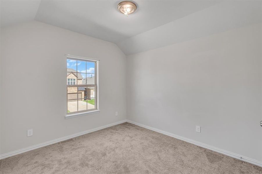 Empty room featuring lofted ceiling and carpet flooring