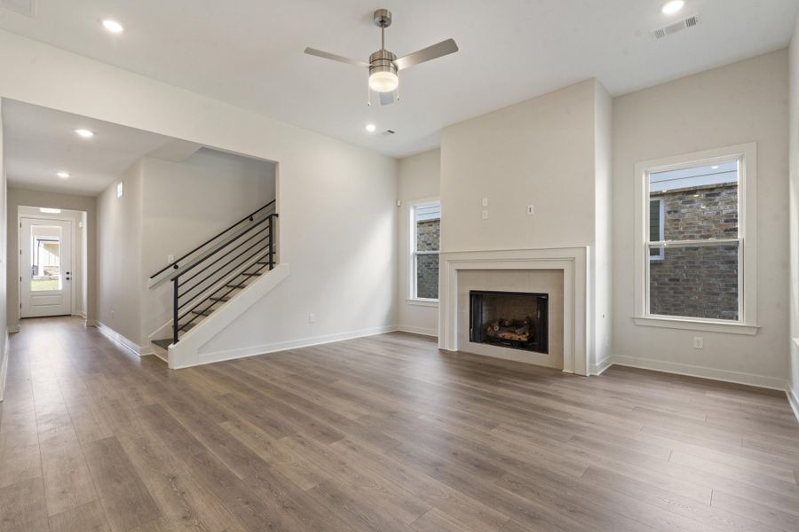 Open-concept living area with wood-finish flooring, a contemporary fireplace, and recessed lighting Open-concept living area with wood-finish flooring, a contemporary fireplace, and recessed lighting