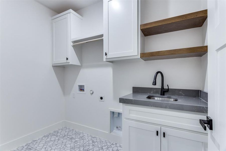 Laundry area featuring cabinet space, baseboards, hookup for a washing machine, hookup for an electric dryer, and a sink