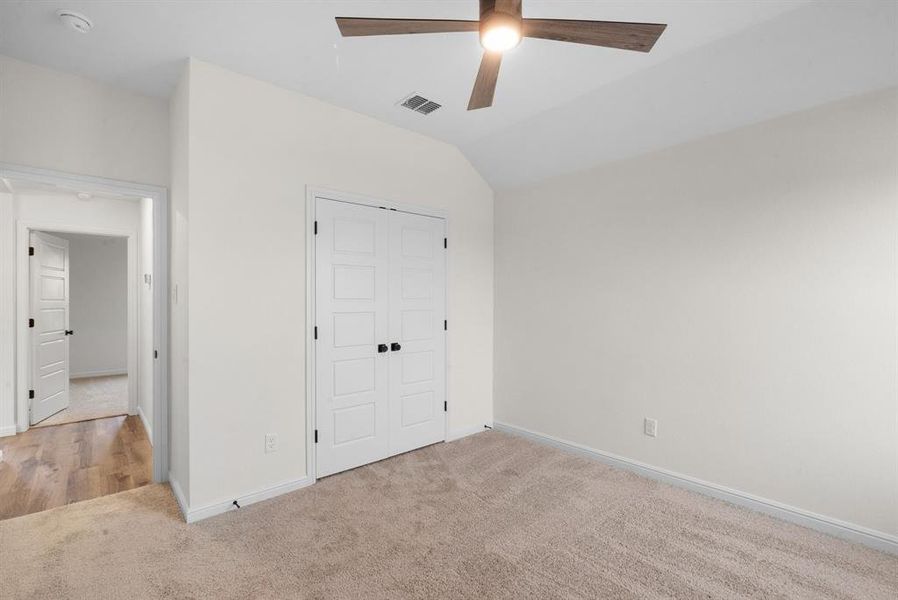 Unfurnished bedroom featuring light carpet, a closet, ceiling fan, and lofted ceiling Unfurnished bedroom featuring light carpet, a closet, ceiling fan, and lofted ceiling