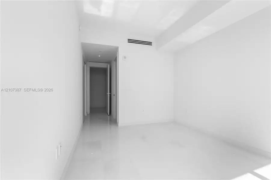 Interior space featuring polished stone-finish flooring, high ceilings with recessed lighting, and a minimalist neutral palette
