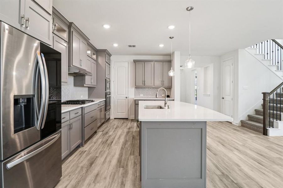 Kitchen with gray cabinets, appliances with stainless steel finishes, light wood-style flooring, and recessed lighting Kitchen with gray cabinets, appliances with stainless steel finishes, light wood-style flooring, and recessed lighting