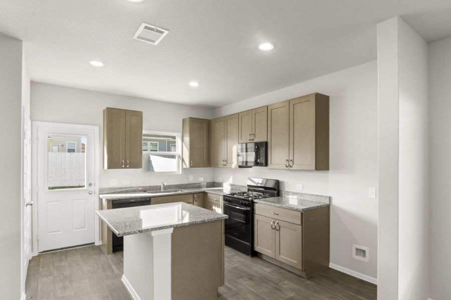 Image of a kitchen with a center island with granite counter tops, brown cabinets and black appliances