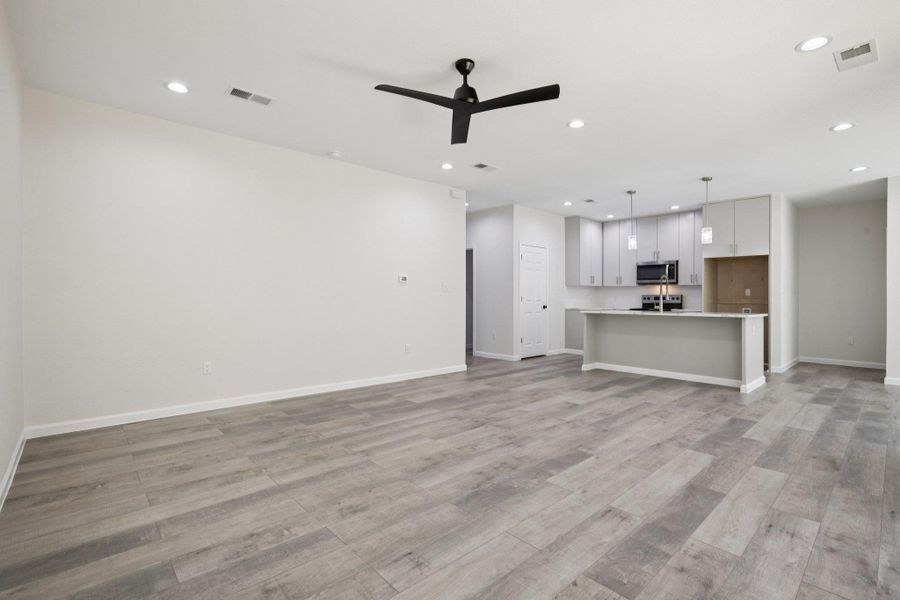 Unfurnished living room featuring a ceiling fan, recessed lighting, and  light wood-type laminate flooring