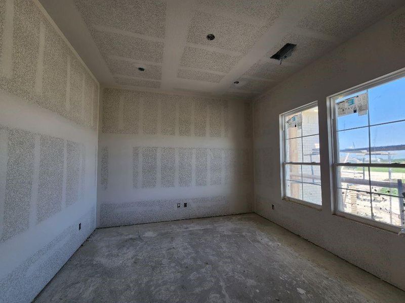 Interior space with unfinished drywall, a tray ceiling, and two large double-hung windows