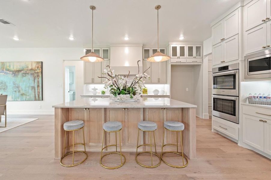 Kitchen featuring white cabinetry, a center island, light hardwood / wood-style floors, and stainless steel appliances