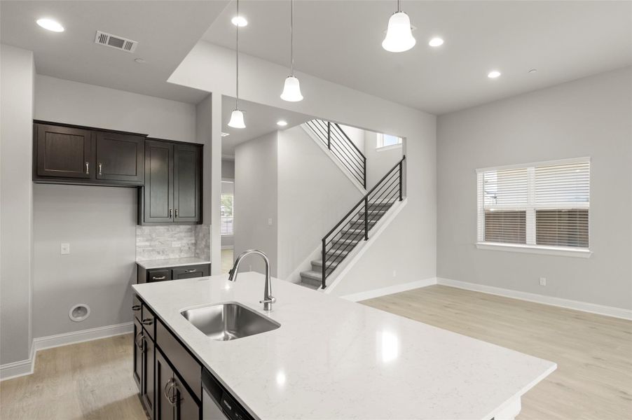 Kitchen featuring light wood-style flooring, pendant lighting, decorative backsplash, light stone counters, and recessed lighting Kitchen featuring light wood-style flooring, pendant lighting, decorative backsplash, light stone counters, and recessed lighting