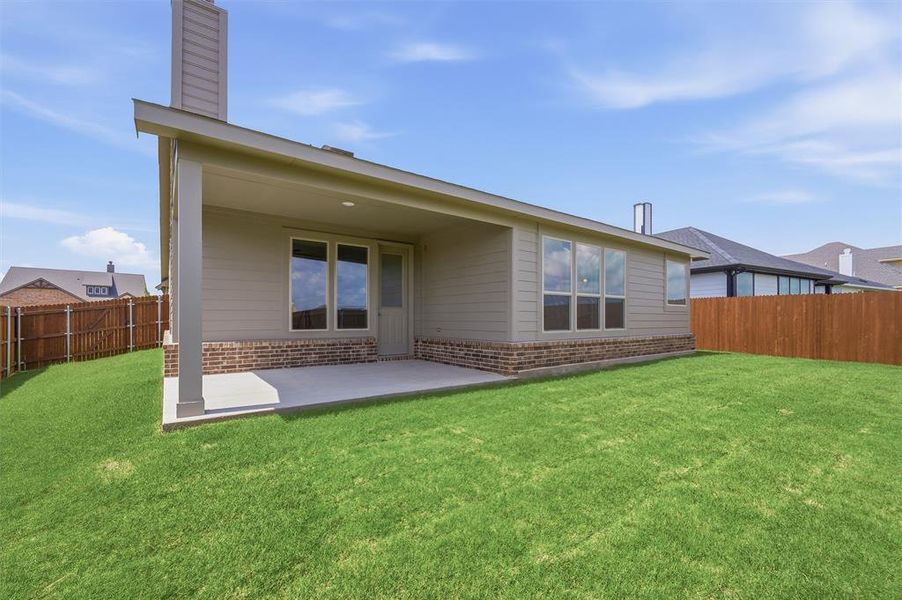 Expansive backyard featuring a covered patio with concrete flooring, siding exterior with brick accents, and a privacy fence
