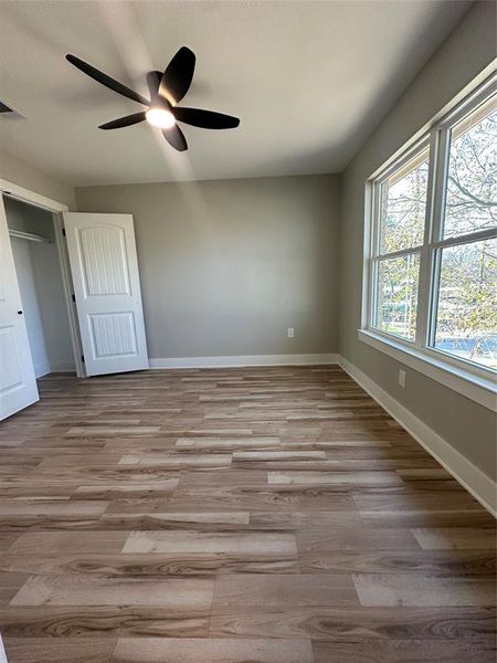 Unfurnished bedroom featuring light wood-type flooring, ceiling fan, and a closet