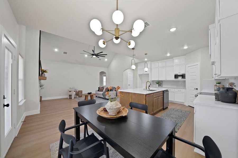 Dining space with arched walkways, light wood finished floors, lofted ceiling, a chandelier, and recessed lighting Dining space with arched walkways, light wood finished floors, lofted ceiling, a chandelier, and recessed lighting