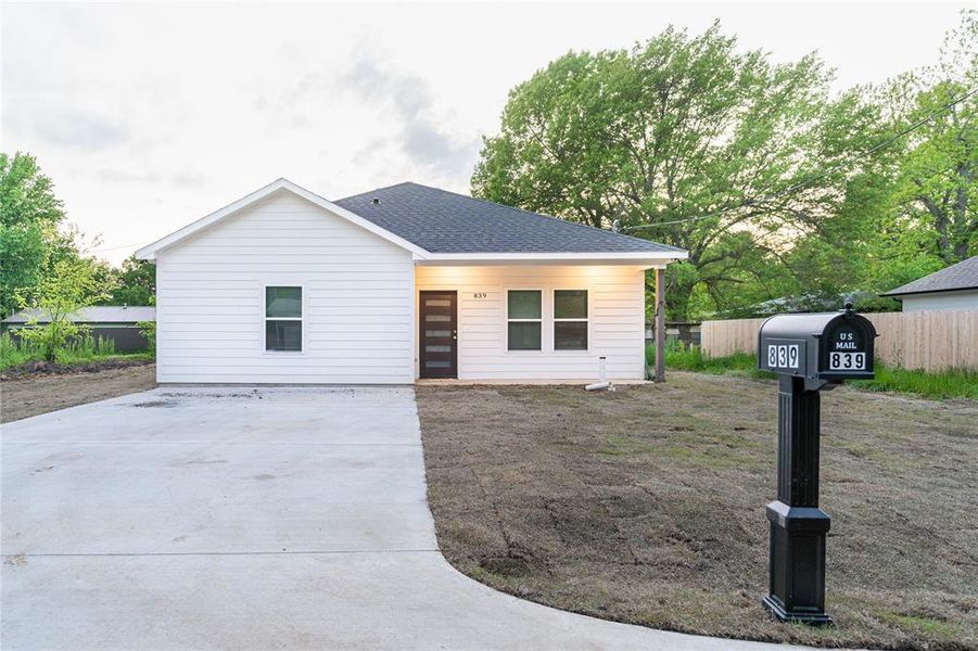 View of front of property featuring driveway, roof with shingles, and fence View of front of property featuring driveway, roof with shingles, and fence