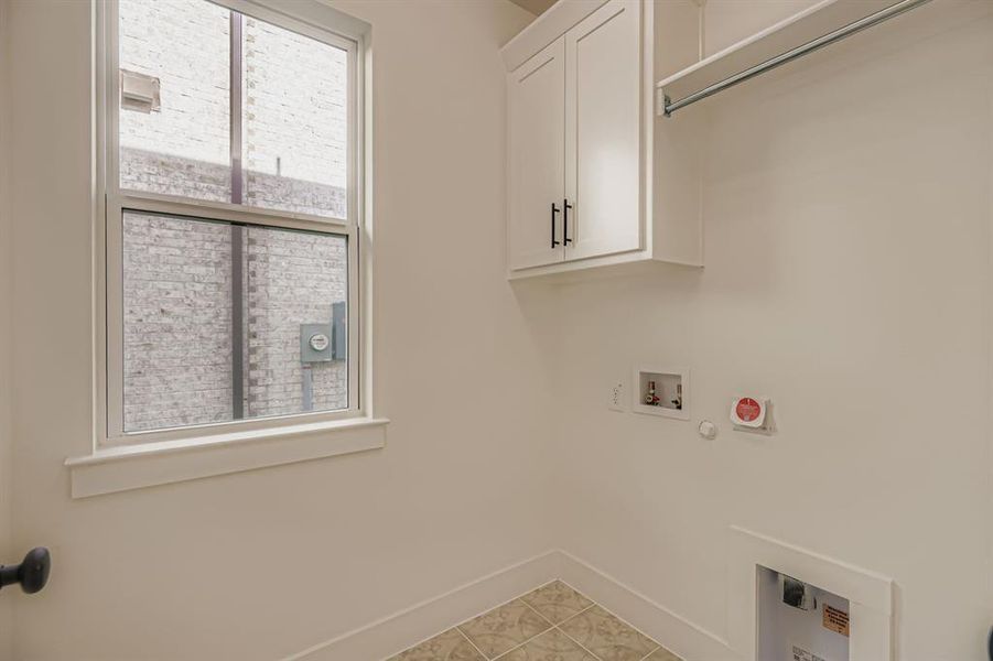 Washroom with gas dryer hookup, light tile patterned floors, hookup for a washing machine, and cabinet space Washroom with gas dryer hookup, light tile patterned floors, hookup for a washing machine, and cabinet space