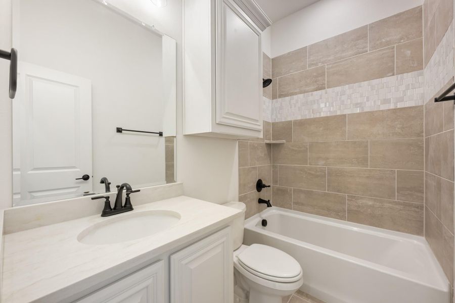 Bathroom with white vanity, quartz countertop, and tiled tub-shower combo with beige tile surround Bathroom with white vanity, quartz countertop, and tiled tub-shower combo with beige tile surround