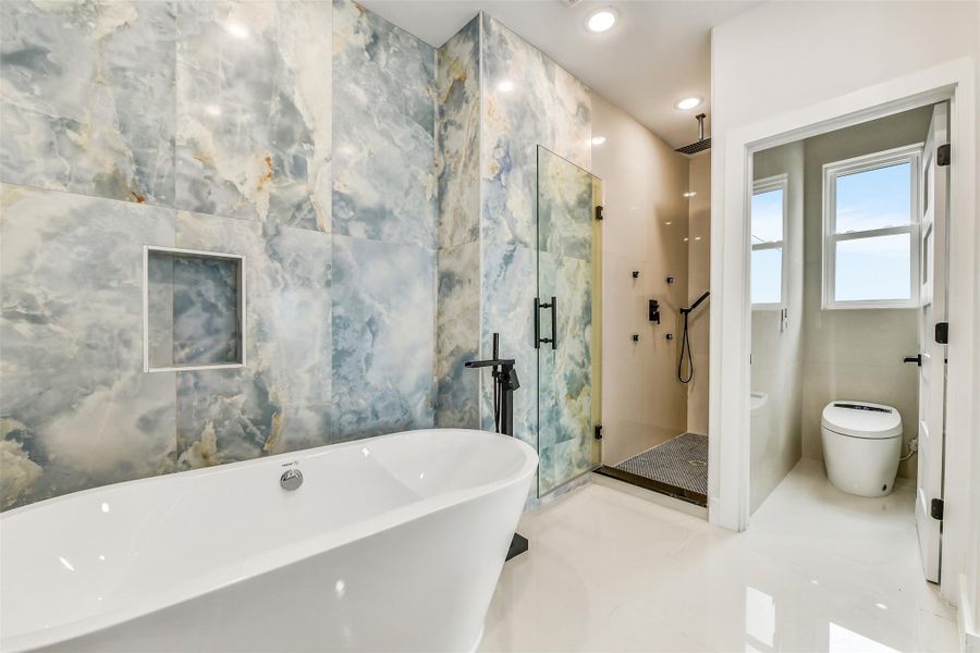 Spa days can begin at home. Designer tile surrounds the freestanding tub and glass shower, creating a primary bath that feels indulgent, modern and deeply relaxing. Spa days can begin at home. Designer tile surrounds the freestanding tub and glass shower, creating a primary bath that feels indulgent, modern and deeply relaxing.