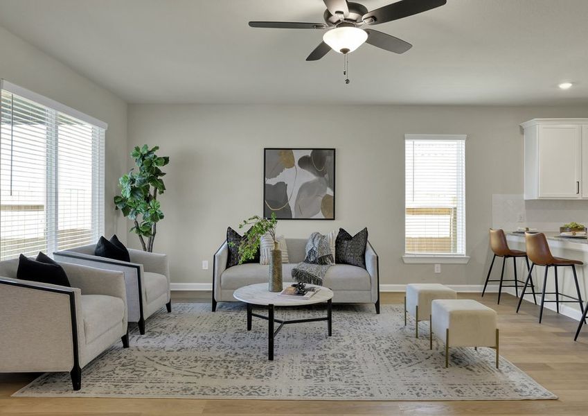 Living room with staged seating and a ceiling fan, open to the kitchen and dining area beyond.