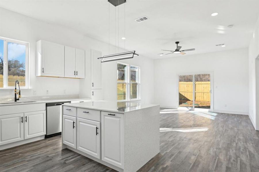 Kitchen featuring visible vents, white cabinetry, a sink, wood finished floors, and dishwasher