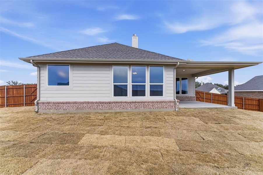 Rear view of property featuring a fenced backyard, a patio, a chimney, a shingled roof, and brick siding