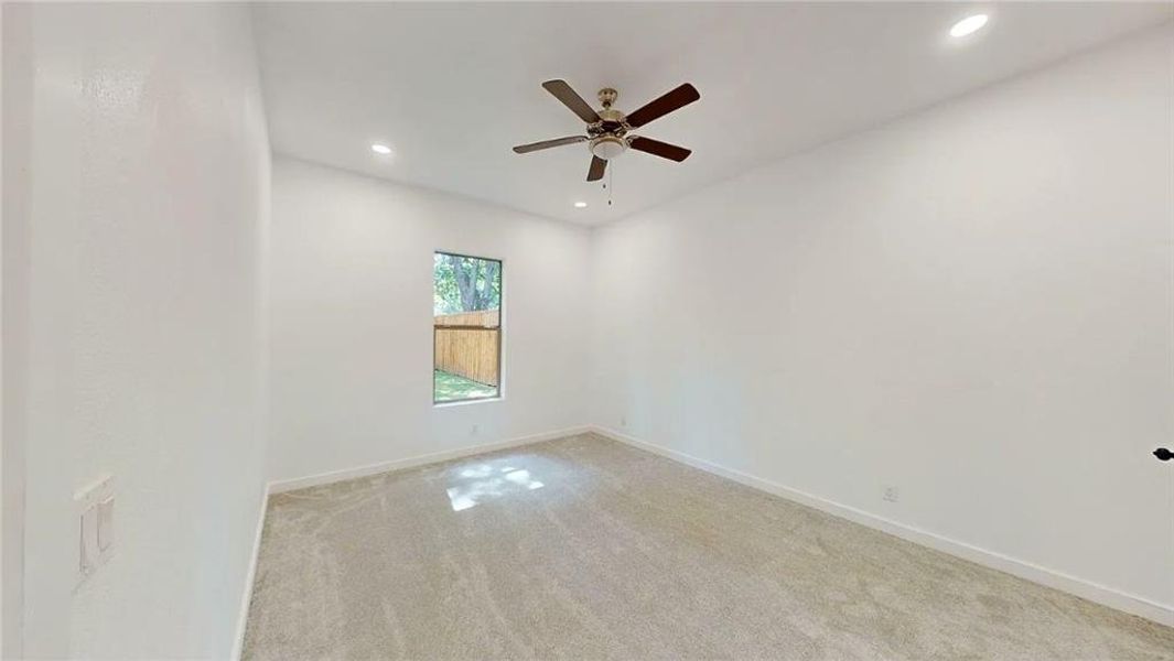 Bright room featuring neutral-toned carpet flooring, a window with a backyard outlook, recessed lighting, and a ceiling fan