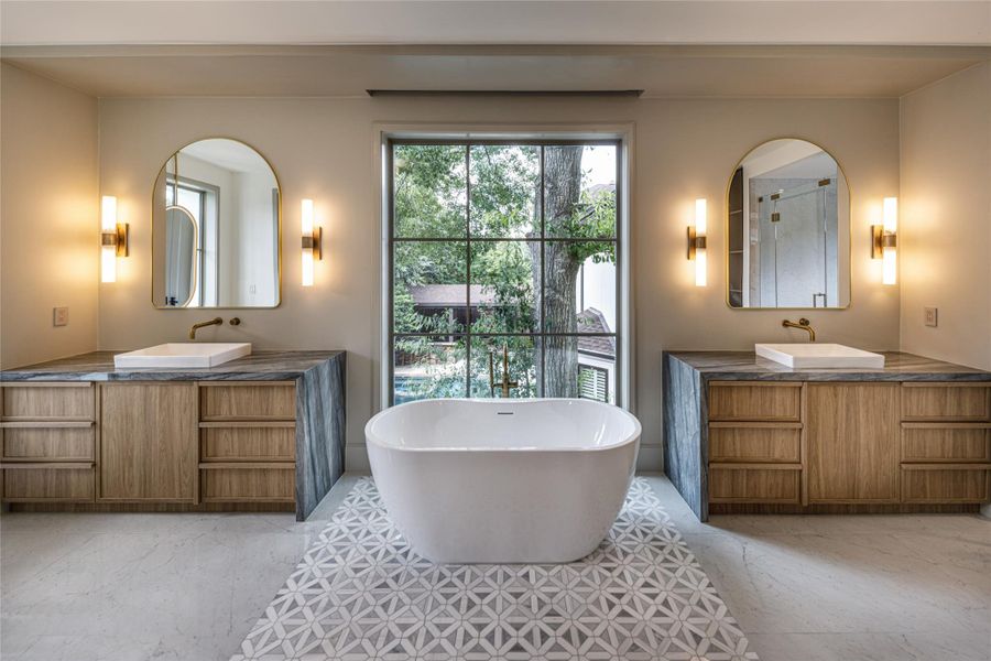 Symmetry done right. The soaking tub takes center stage beneath a picture window, with matching vanities and illuminated mirrors on either side. Clean, calm, and incredibly well considered.