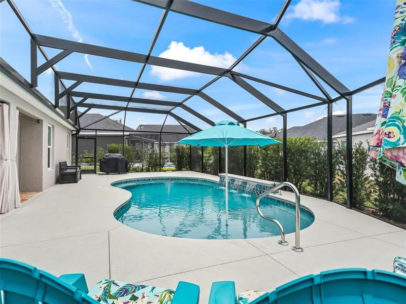 Pool area with expanded patio space, shallow shelf with umbrella, and three waterfalls