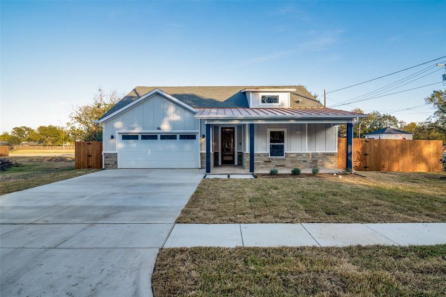 View of front of home with covered porch, a garage, and a front yard