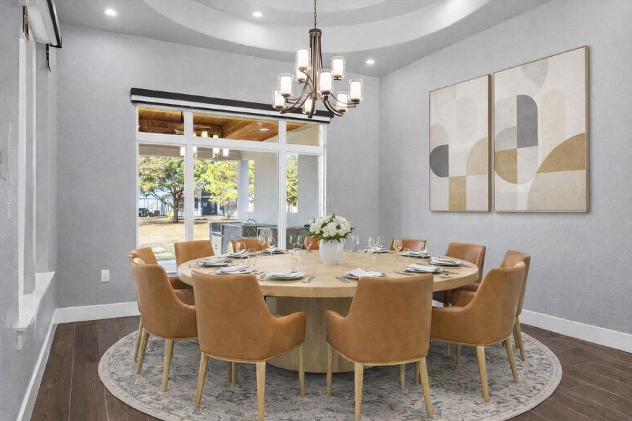 second Dining room featuring dark wood-type flooring, a raised ceiling, and hanging lights. virtually staged