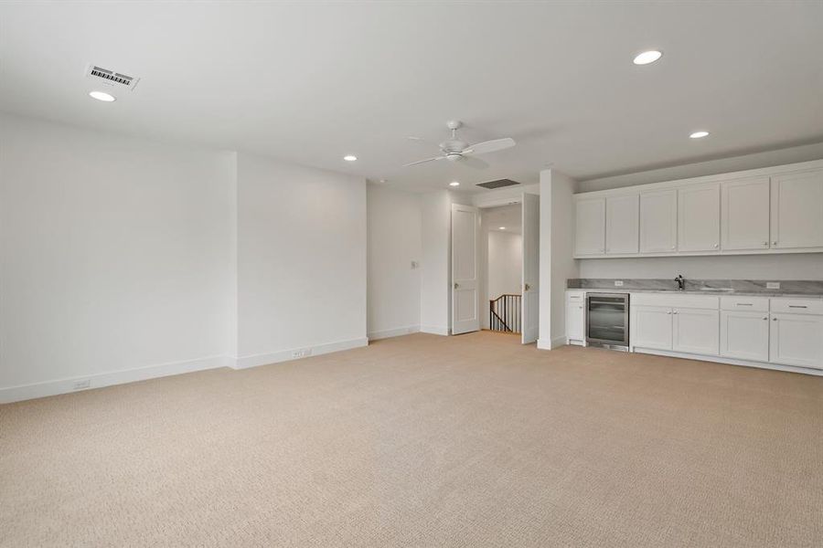 The massive game room features ample built in storage, a sink, and beverage fridge.