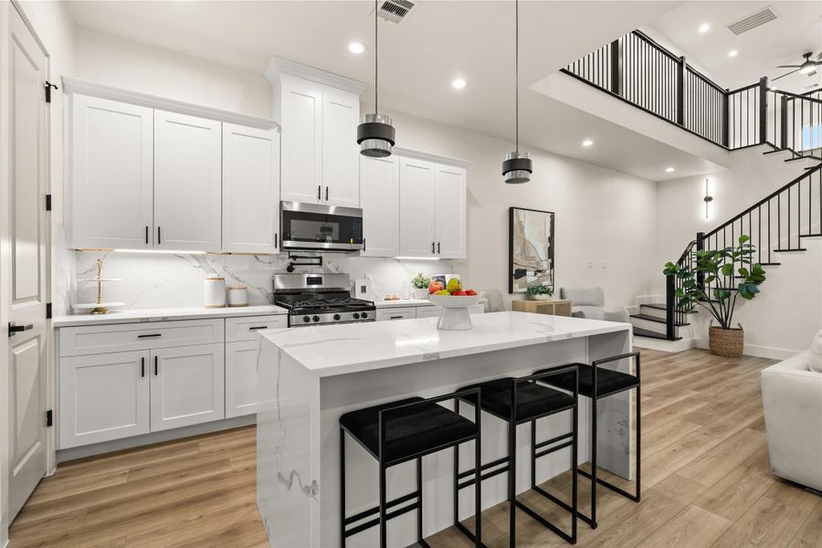 Island view with bold pendant lighting and open sightlines into the living room Island view with bold pendant lighting and open sightlines into the living room