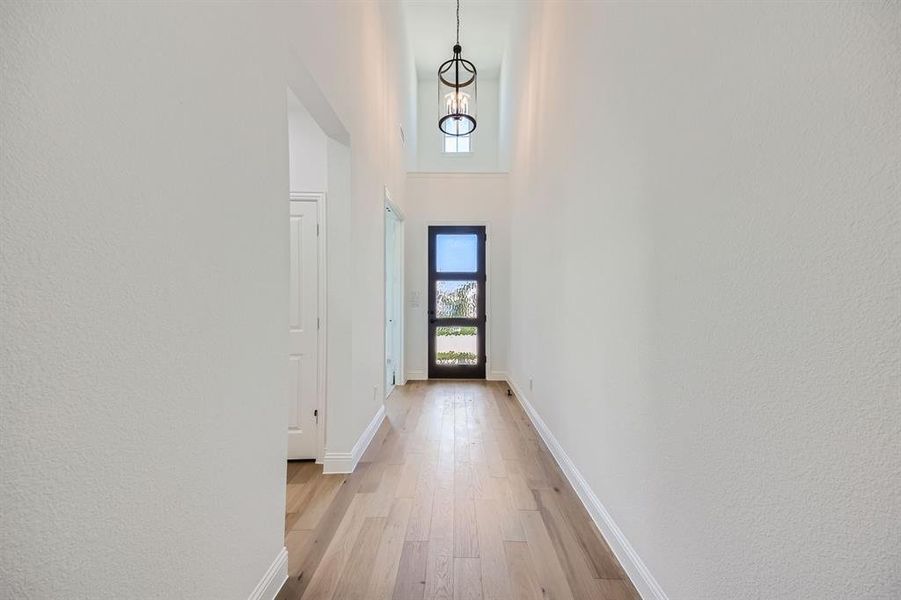 Hall with light hardwood / wood-style flooring and a high ceiling