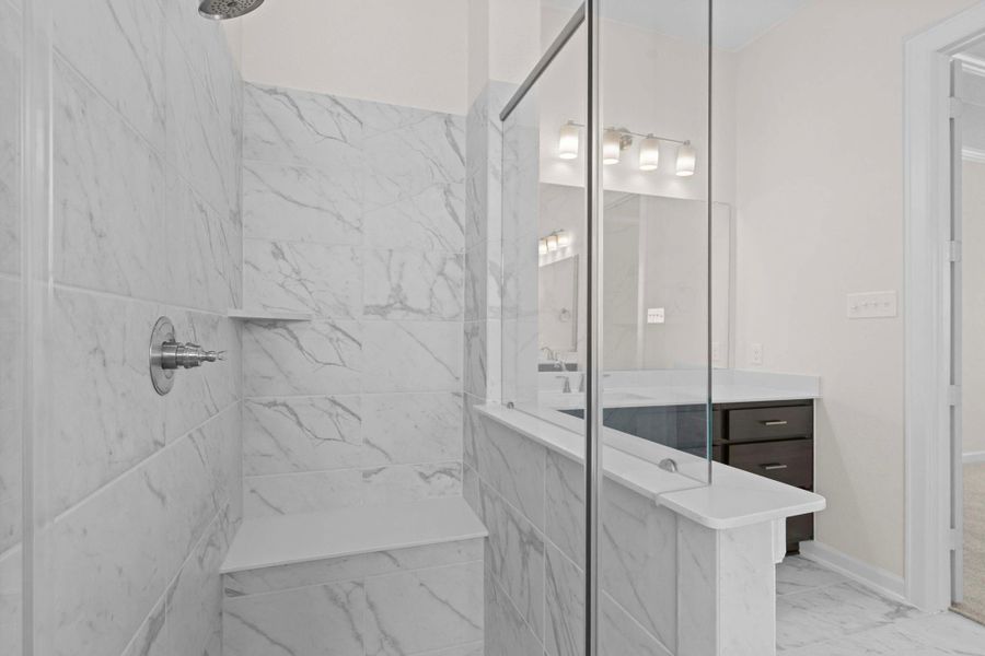 Luxurious glass-enclosed shower with marble-style tile surround, offering a clean and modern spa-like design.