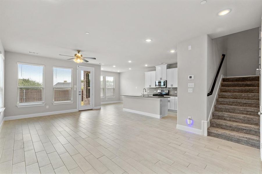 Unfurnished living room with a wealth of natural light, ceiling fan, and light hardwood / wood-style floors